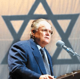 The satanist poses with his symbol of evil, Hagee spruiks the Apartheid state professionally.